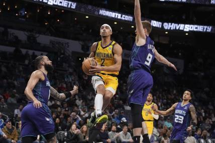 Feb 12, 2024; Charlotte, North Carolina, USA; Indiana Pacers guard Andrew Nembhard (2) goes up for a layup defended but Charlotte Hornets forward Davis Bertans (9) during the second quarter at Spectrum Center. Mandatory Credit: Jim Dedmon-USA TODAY Sports