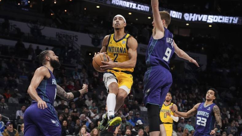 Feb 12, 2024; Charlotte, North Carolina, USA; Indiana Pacers guard Andrew Nembhard (2) goes up for a layup defended but Charlotte Hornets forward Davis Bertans (9) during the second quarter at Spectrum Center. Mandatory Credit: Jim Dedmon-USA TODAY Sports