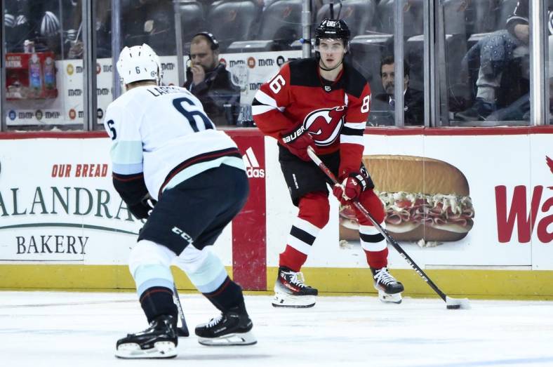 Feb 12, 2024; Newark, New Jersey, USA; New Jersey Devils center Jack Hughes (86) skates with the puck while being defended by Seattle Kraken defenseman Adam Larsson (6) during the second period at Prudential Center. Mandatory Credit: John Jones-USA TODAY Sports