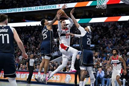 Feb 12, 2024; Dallas, Texas, USA; Washington Wizards forward Kyle Kuzma (33) drives to the basket between Dallas Mavericks forward P.J. Washington (25) and center Daniel Gafford (21) during the second quarter at the American Airlines Center. Mandatory Credit: Jerome Miron-USA TODAY Sports