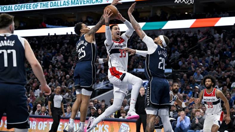 Feb 12, 2024; Dallas, Texas, USA; Washington Wizards forward Kyle Kuzma (33) drives to the basket between Dallas Mavericks forward P.J. Washington (25) and center Daniel Gafford (21) during the second quarter at the American Airlines Center. Mandatory Credit: Jerome Miron-USA TODAY Sports