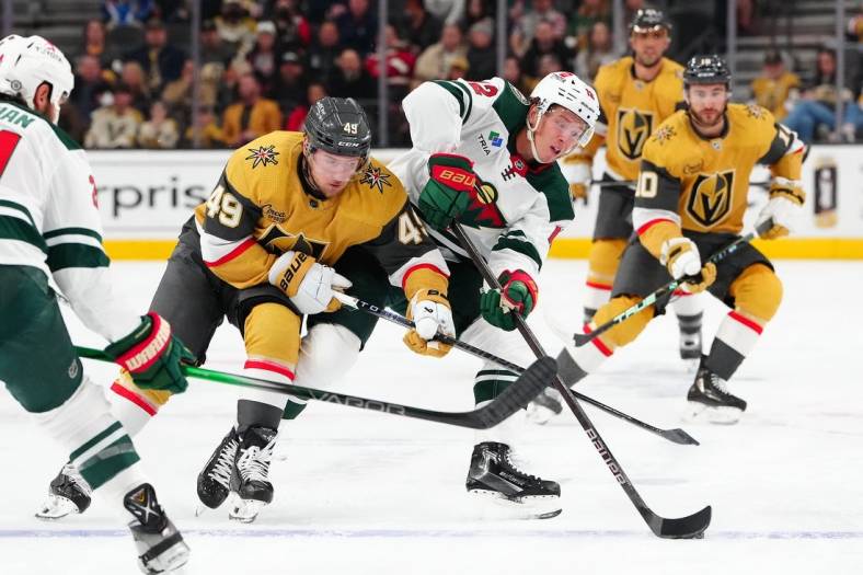 Feb 12, 2024; Las Vegas, Nevada, USA; Minnesota Wild left wing Matt Boldy (12) keeps the puck away from Vegas Golden Knights center Ivan Barbashev (49) during the first period at T-Mobile Arena. Mandatory Credit: Stephen R. Sylvanie-USA TODAY Sports