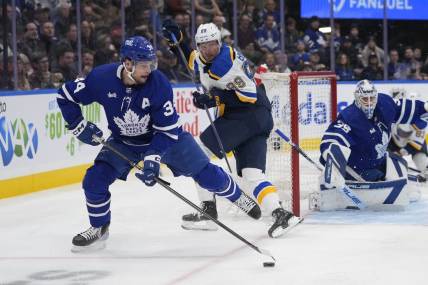 Feb 13, 2024; Toronto, Ontario, CAN; Toronto Maple Leafs forward Auston Matthews (34) goes to clear a rebound as St. Louis Blues forward Pavel Buchnevich (89) looks on during the second period Scotiabank Arena. Mandatory Credit: John E. Sokolowski-USA TODAY Sports