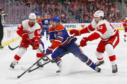Feb 13, 2024; Edmonton, Alberta, CAN; Edmonton Oilers forward Connor McDavid (97) protects the puck from Detroit Red Wings defensemen Moritz Seider (53) and defensemen Jake Walman (96) at Rogers Place. Mandatory Credit: Perry Nelson-USA TODAY Sports