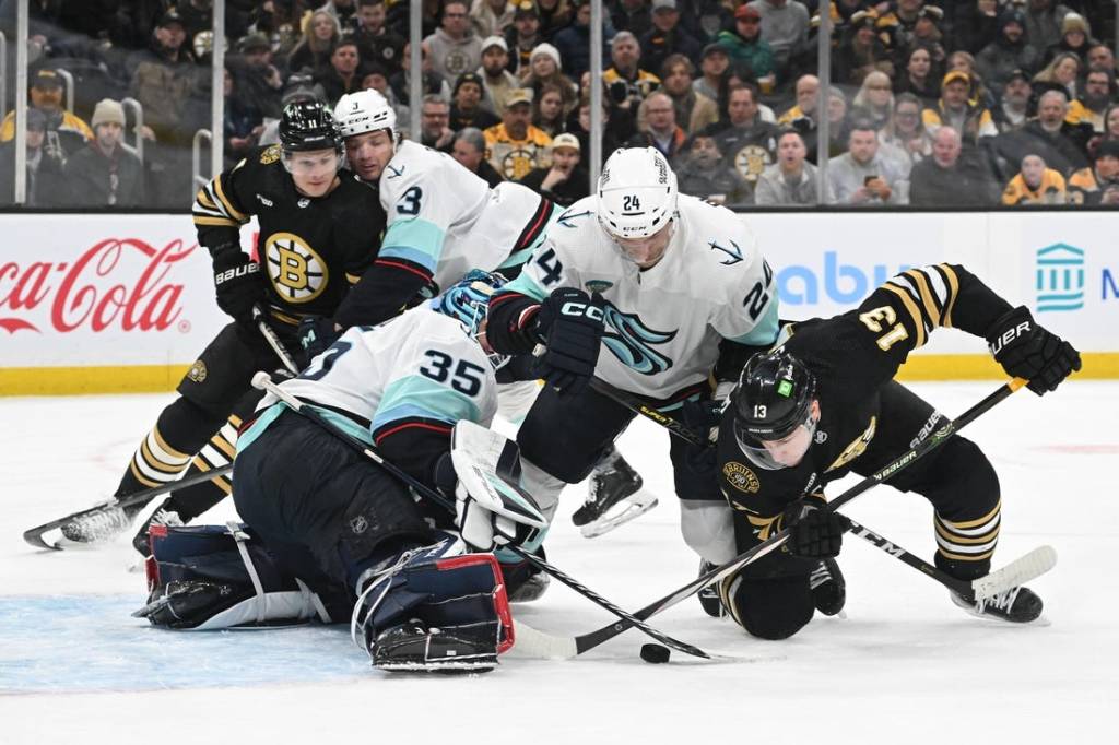 Feb 15, 2024; Boston, Massachusetts, USA; Boston Bruins center Charlie Coyle (13) battles for the puck against Seattle Kraken goaltender Joey Daccord (35) and defenseman Jamie Oleksiak (24) during the first period at TD Garden. Mandatory Credit: Brian Fluharty-USA TODAY Sports