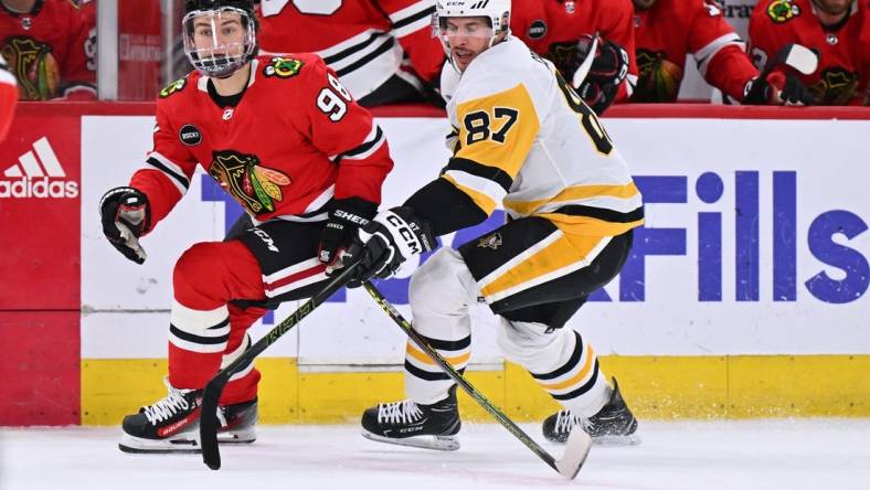 Feb 15, 2024; Chicago, Illinois, USA; Chicago Blackhawks forward Connor Bedard (98) and Pittsburgh Penguins forward Sidney Crosby (87) chase after a loose puck in the first period at United Center. Mandatory Credit: Jamie Sabau-USA TODAY Sports