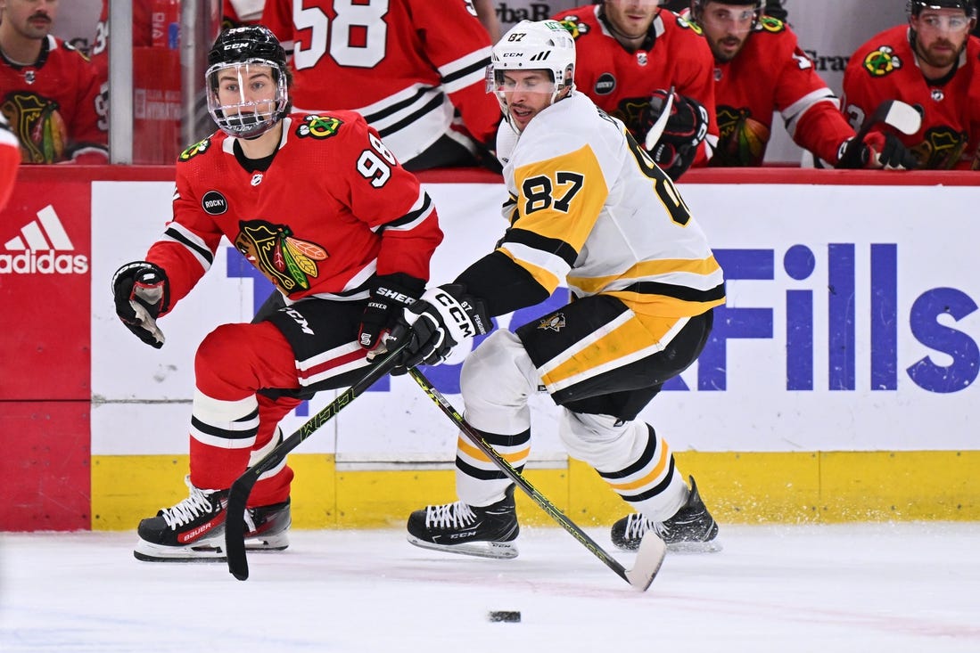 Feb 15, 2024; Chicago, Illinois, USA; Chicago Blackhawks forward Connor Bedard (98) and Pittsburgh Penguins forward Sidney Crosby (87) chase after a loose puck in the first period at United Center. Mandatory Credit: Jamie Sabau-USA TODAY Sports