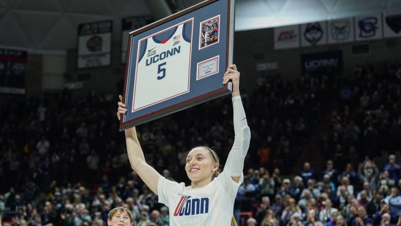 Feb 16, 2024; Storrs, Connecticut, USA; UConn Huskies guard Paige Bueckers (5) holds up her jersey during senior night after defeating the Georgetown Hoyas at Harry A. Gampel Pavilion. Mandatory Credit: David Butler II-USA TODAY Sports