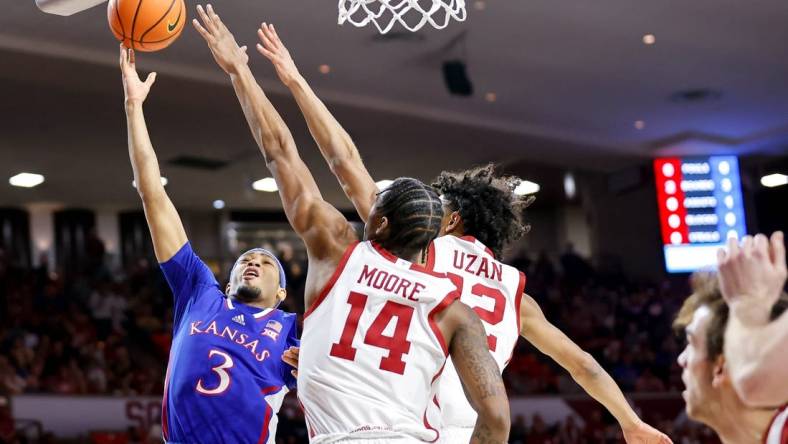 Kansas guard Dajuan Harris Jr. (3) lays up the ball past Oklahoma guard Milos Uzan (12) and Oklahoma forward Jalon Moore (14) in the first half during an NCAA basketball game between The University of Oklahoma (OU) and The University of Kansas (KU), at the Lloyd Noble Center in Norman Okla., on Saturday, Feb. 17, 2024.