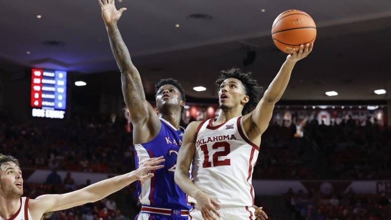 Feb 17, 2024; Norman, Oklahoma, USA; Oklahoma Sooners guard Milos Uzan (12) goes up for a basket beside Kansas Jayhawks forward K.J. Adams Jr. (24) during the second half at Lloyd Noble Center. Mandatory Credit: Alonzo Adams-USA TODAY Sports