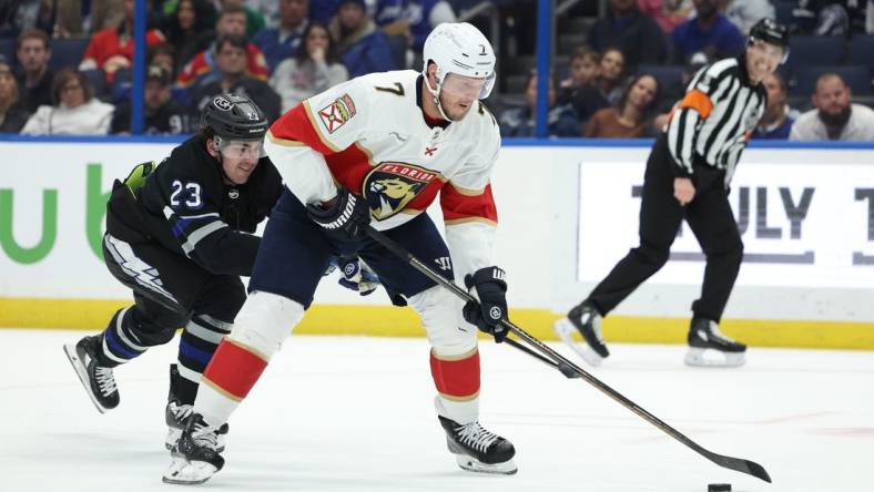 Feb 17, 2024; Tampa, Florida, USA;  Florida Panthers defenseman Dmitry Kulikov (7) controls the puck from Tampa Bay Lightning center Michael Eyssimont (23) in the second period at Amalie Arena. Mandatory Credit: Nathan Ray Seebeck-USA TODAY Sports