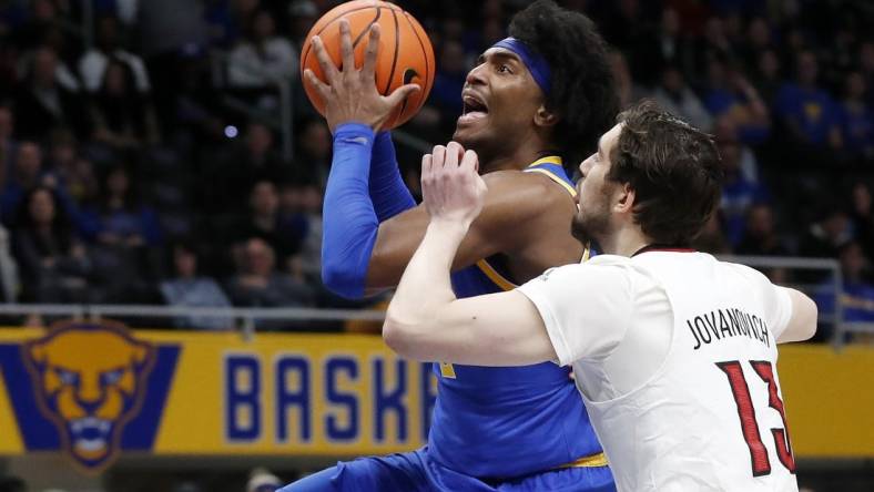 Feb 17, 2024; Pittsburgh, Pennsylvania, USA;  Pittsburgh Panthers forward Blake Hinson (left) goes to the basket against Louisville Cardinals forward Danilo Jovanovich (13) during the first half at the Petersen Events Center. Mandatory Credit: Charles LeClaire-USA TODAY Sports