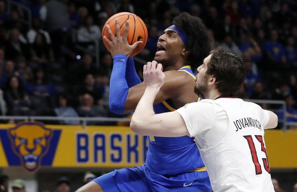 Feb 17, 2024; Pittsburgh, Pennsylvania, USA;  Pittsburgh Panthers forward Blake Hinson (left) goes to the basket against Louisville Cardinals forward Danilo Jovanovich (13) during the first half at the Petersen Events Center. Mandatory Credit: Charles LeClaire-USA TODAY Sports