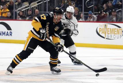 Feb 18, 2024; Pittsburgh, Pennsylvania, USA;  Pittsburgh Penguins center Sidney Crosby (87) skates with the puck ahead of Los Angeles Kings center Anze Kopitar (11) during the third period at PPG Paints Arena.  Los Angeles won 2-1. Mandatory Credit: Charles LeClaire-USA TODAY Sports