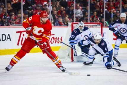 Feb 19, 2024; Calgary, Alberta, CAN; Calgary Flames center Jonathan Huberdeau (10) passes the puck against the Winnipeg Jets during the second period at Scotiabank Saddledome. Mandatory Credit: Sergei Belski-USA TODAY Sports