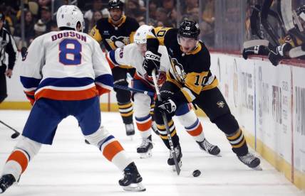 Feb 20, 2024; Pittsburgh, Pennsylvania, USA; Pittsburgh Penguins left wing Drew O'Connor (10) skates up ice with the puck as New York Islanders defenseman Noah Dobson (8) defends during the first period  at PPG Paints Arena. Mandatory Credit: Charles LeClaire-USA TODAY Sports