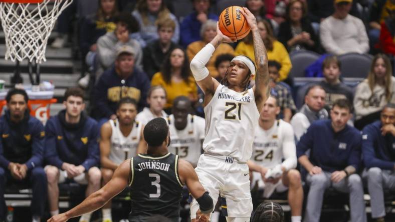 Feb 20, 2024; Morgantown, West Virginia, USA; West Virginia Mountaineers guard RaeQuan Battle (21) shoots a jumper over UCF Knights guard Darius Johnson (3) during the second half at WVU Coliseum. Mandatory Credit: Ben Queen-USA TODAY Sports