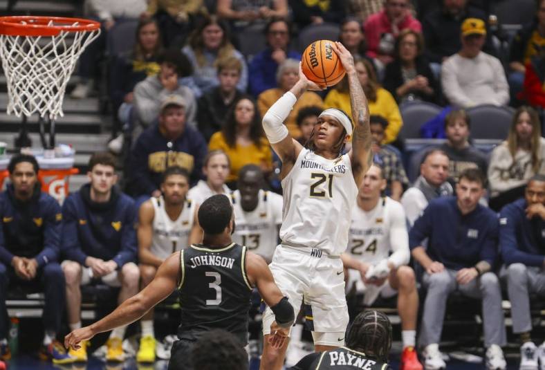 Feb 20, 2024; Morgantown, West Virginia, USA; West Virginia Mountaineers guard RaeQuan Battle (21) shoots a jumper over UCF Knights guard Darius Johnson (3) during the second half at WVU Coliseum. Mandatory Credit: Ben Queen-USA TODAY Sports