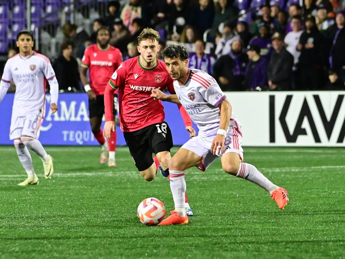 Feb 21, 2024; Langford, BC, Canada; Orlando City midfielder Felipe Martins (8) controls the ball against Cavalry FC midfielder Mael Henry (18) during the second half at Starlight Stadium. Mandatory Credit: Simon Fearn-USA TODAY Sports