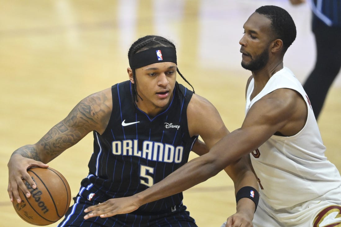 Feb 22, 2024; Cleveland, Ohio, USA; Orlando Magic forward Paolo Banchero (5) dribbles beside Cleveland Cavaliers forward Evan Mobley (4) in the first quarter at Rocket Mortgage FieldHouse. Mandatory Credit: David Richard-USA TODAY Sports