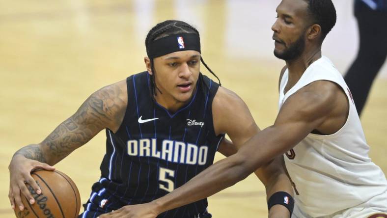 Feb 22, 2024; Cleveland, Ohio, USA; Orlando Magic forward Paolo Banchero (5) dribbles beside Cleveland Cavaliers forward Evan Mobley (4) in the first quarter at Rocket Mortgage FieldHouse. Mandatory Credit: David Richard-USA TODAY Sports