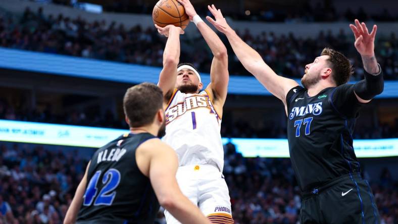 Feb 22, 2024; Dallas, Texas, USA; Phoenix Suns guard Devin Booker (1) shoots over Dallas Mavericks guard Luka Doncic (77) and Dallas Mavericks forward Maxi Kleber (42) during the second half at American Airlines Center. Mandatory Credit: Kevin Jairaj-USA TODAY Sports