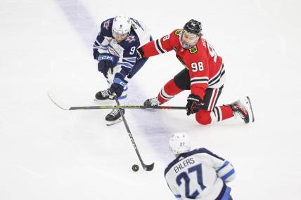 Feb 23, 2024; Chicago, Illinois, USA; Winnipeg Jets left wing Alex Iafallo (9) battles for the puck with Chicago Blackhawks center Connor Bedard (98) during the first period at United Center. Mandatory Credit: Kamil Krzaczynski-USA TODAY Sports