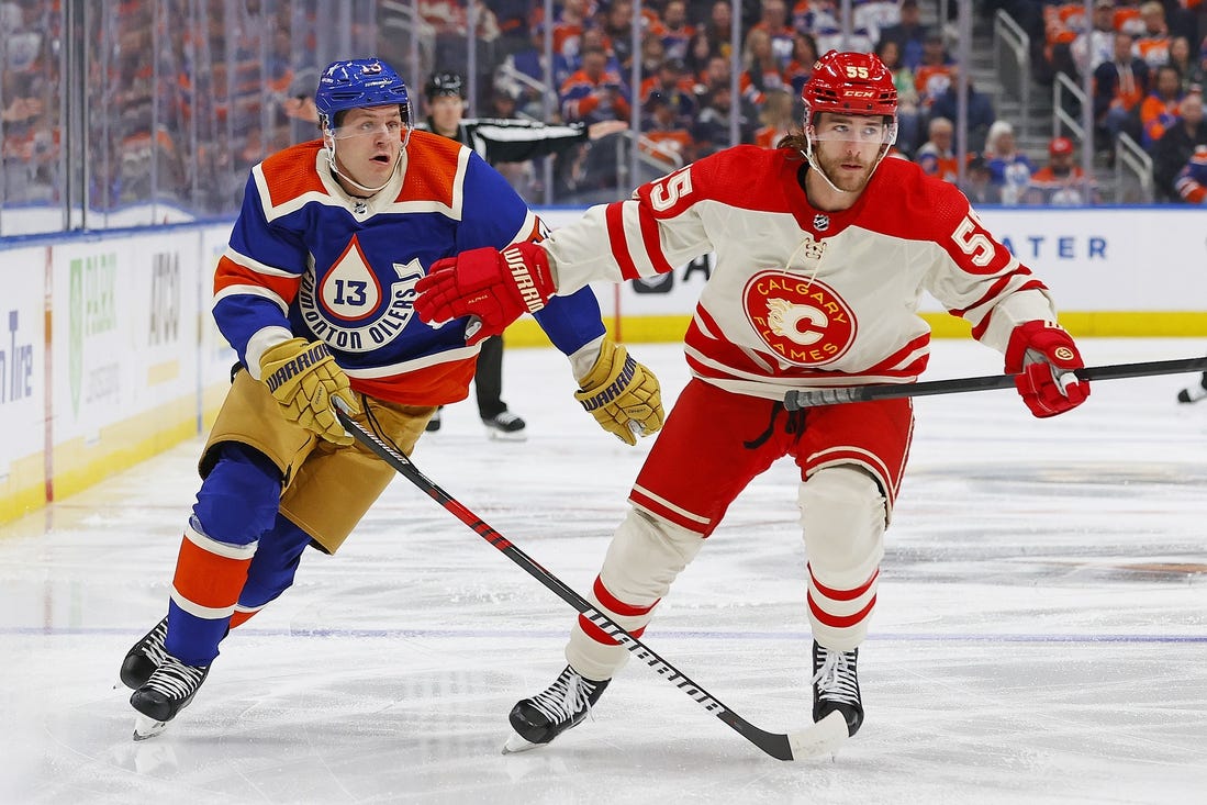 Feb 24, 2024; Edmonton, Alberta, CAN; Calgary Flames defensemen Noah Hanifin (55) and Edmonton Oilers forward Mattias Janmark (13) chase a loose puck during the first period at Rogers Place. Mandatory Credit: Perry Nelson-USA TODAY Sports