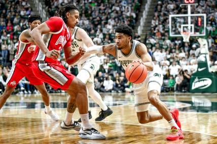 Michigan State's Jaden Akins, right, moves the ball as Ohio State's Devin Royal defends during the first half on Sunday, Feb. 25, 2024, at the Breslin Center in East Lansing.
