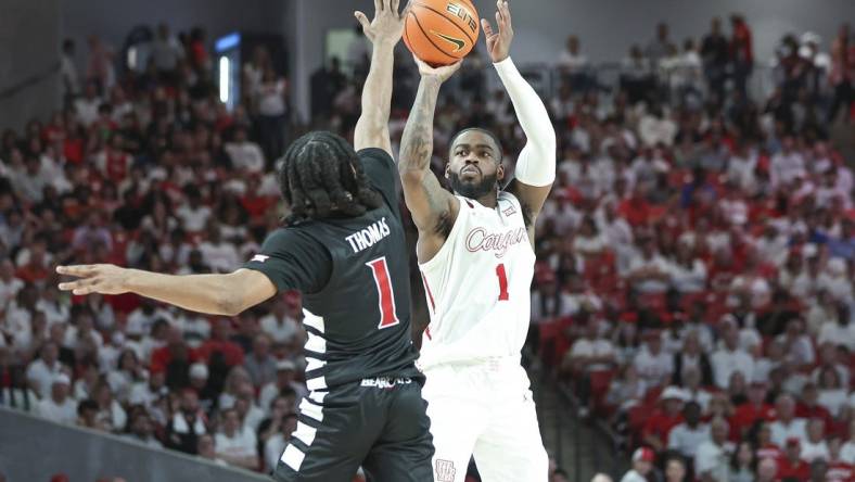 Feb 27, 2024; Houston, Texas, USA; Houston Cougars guard Jamal Shead (1) shoots the ball as Cincinnati Bearcats guard Day Day Thomas (1) defends during the first half at Fertitta Center. Mandatory Credit: Troy Taormina-USA TODAY Sports