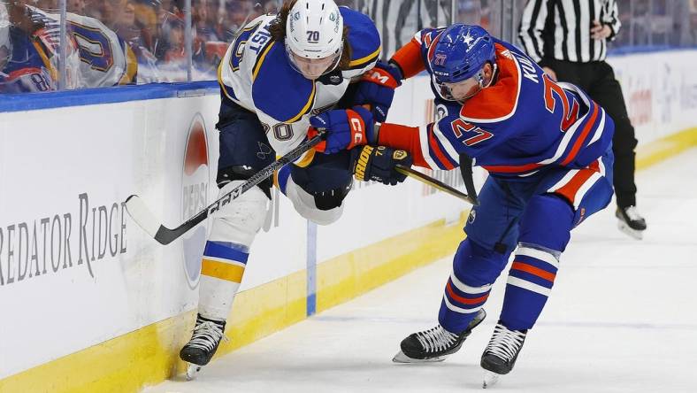 Feb 28, 2024; Edmonton, Alberta, CAN; St. Louis Blues forward Oskar Sundqvist (70) and Edmonton Oilers defensemen Brett Kulak (27)  battle for a loose puck  during the second period at Rogers Place. Mandatory Credit: Perry Nelson-USA TODAY Sports
