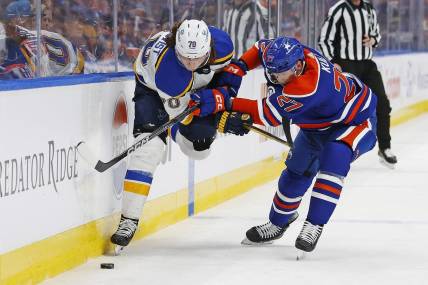 Feb 28, 2024; Edmonton, Alberta, CAN; St. Louis Blues forward Oskar Sundqvist (70) and Edmonton Oilers defensemen Brett Kulak (27)  battle for a loose puck  during the second period at Rogers Place. Mandatory Credit: Perry Nelson-USA TODAY Sports