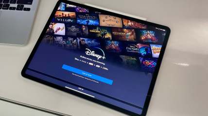 Disney Plus Bundle sign up page on an iPad sitting on a desk next to a MacBook