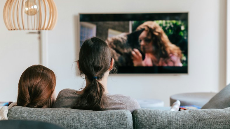 Woman and child sitting on the couch watching TV together