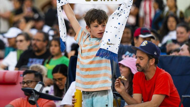 Jul 26, 2023; Los Angeles, California, USA; A young fan holds up a U.S. Women's National Team scarf in Los Angeles. Mandatory Credit: Robert Hanashiro-USA TODAY