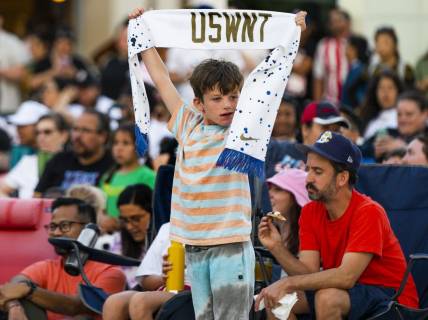 Jul 26, 2023; Los Angeles, California, USA; A young fan holds up a U.S. Women's National Team scarf in Los Angeles. Mandatory Credit: Robert Hanashiro-USA TODAY