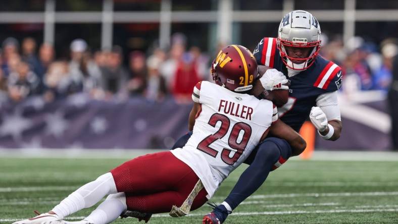 Nov 5, 2023; Foxborough, Massachusetts, USA; Washington Commanders cornerback Kendall Fuller (29) tackles New England Patriots receiver JuJu Smith-Schuster (7) during the second half at Gillette Stadium. Mandatory Credit: Paul Rutherford-USA TODAY Sports