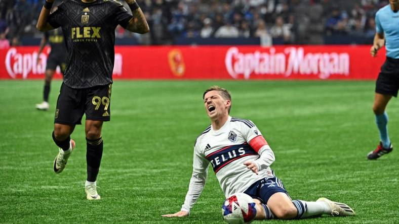 Nov 5, 2023; Vancouver, British Columbia, CAN; Vancouver Whitecaps midfielder Ryan Gauld (25) falls to the pitch against Los Angeles FC forward Denis Bouanga (99) during the second half of game two in a round one match of the 2023 MLS Cup Playoffs at BC Place. Mandatory Credit: Simon Fearn-USA TODAY Sports