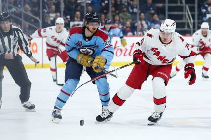 Dec 4, 2023; Winnipeg, Manitoba, CAN; Carolina Hurricanes defenseman Brady Skjei (76) and Winnipeg Jets forward Kyle Connor (81) go for the puck during the second period at Canada Life Centre. Mandatory Credit: Terrence Lee-USA TODAY Sports