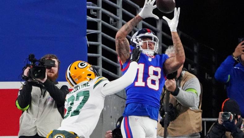 Dec 11, 2023; East Rutherford, New Jersey, USA; New York Giants wide receiver Isaiah Hodgins (18) catches a touchdown against Green Bay Packers cornerback Carrington Valentine (37) during the third quarter at MetLife Stadium. Mandatory Credit: Robert Deutsch-USA TODAY Sports