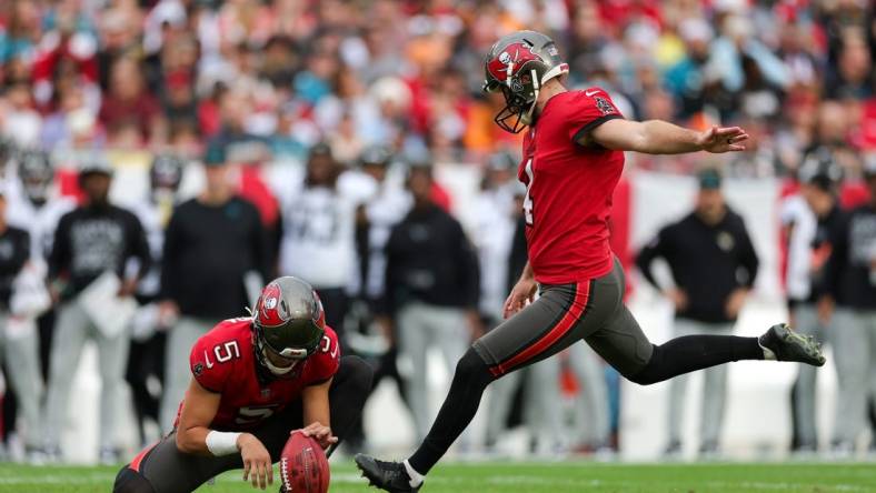 Dec 24, 2023; Tampa, Florida, USA;  Tampa Bay Buccaneers place kicker Chase McLaughlin (4) kicks a field goal held by punter Jake Camarda (5) against the Jacksonville Jaguars in the first quarter at Raymond James Stadium. Mandatory Credit: Nathan Ray Seebeck-USA TODAY Sports