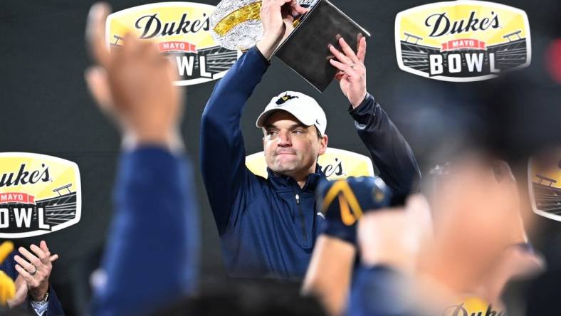 Dec 27, 2023; Charlotte, NC, USA; West Virginia Mountaineers head coach Neal Brown holds up the championship trophy after the game at Bank of America Stadium. Mandatory Credit: Bob Donnan-USA TODAY Sports