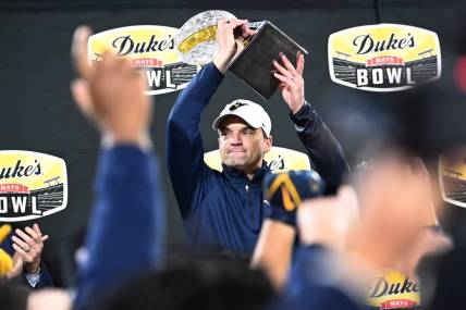 Dec 27, 2023; Charlotte, NC, USA; West Virginia Mountaineers head coach Neal Brown holds up the championship trophy after the game at Bank of America Stadium. Mandatory Credit: Bob Donnan-USA TODAY Sports