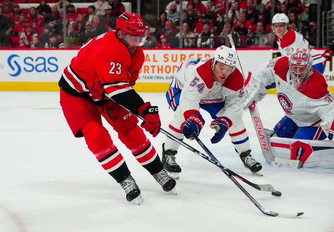 Dec 28, 2023; Raleigh, North Carolina, USA; Carolina Hurricanes right wing Stefan Noesen (23) ties to get his shot by Montreal Canadiens defenseman Jordan Harris (54) during the third period at PNC Arena. Mandatory Credit: James Guillory-USA TODAY Sports