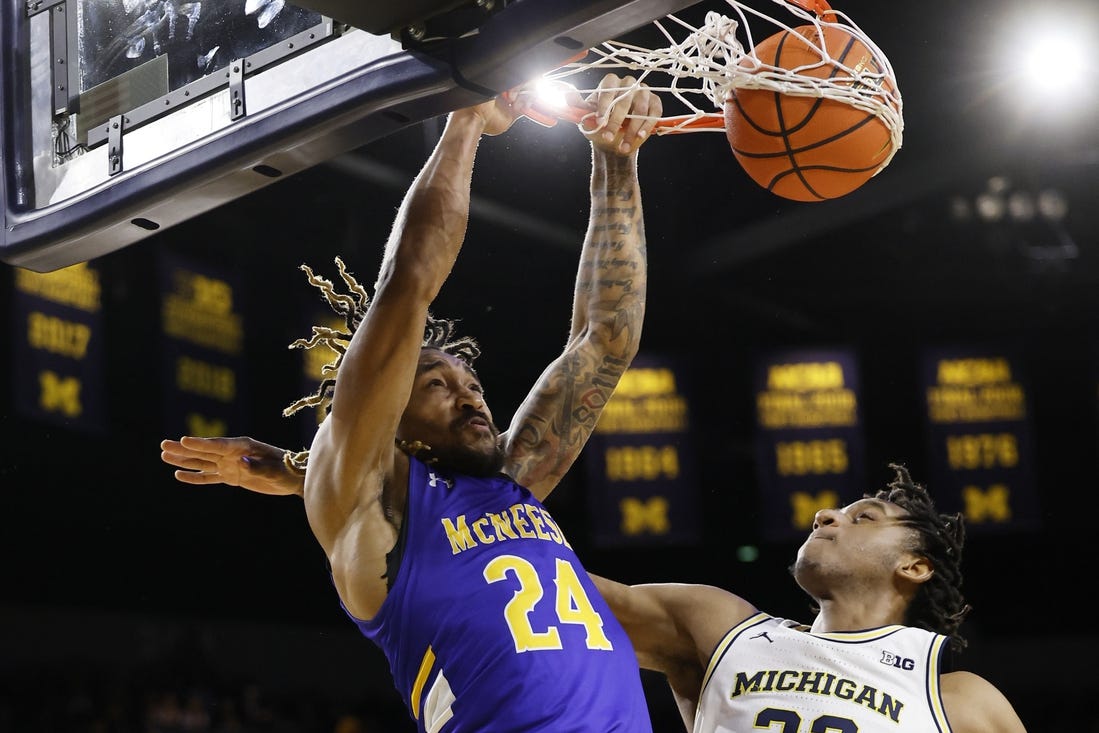 Dec 29, 2023; Ann Arbor, Michigan, USA;  McNeese State Cowboys forward Christian Shumate (24) dunks on Michigan Wolverines forward Tarris Reed Jr. (32) in the second half at Crisler Center. Mandatory Credit: Rick Osentoski-USA TODAY Sports