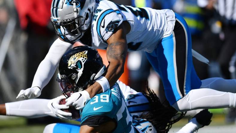 Jacksonville Jaguars wide receiver Jamal Agnew (39) gets tackled by Carolina Panthers cornerback Shaquill Griffin (20) and safety Vonn Bell (24) on a first down pass play to the 5-yard line late in the second quarter. Agnew was injured at the end of the play. The Jacksonville Jaguars hosted the Carolina Panthers at EverBank Stadium in Jacksonville, FL Sunday, December 31, 2023. The Jaguars went in at the half with a 9 to 0 lead. [Bob Self/Florida Times-Union]