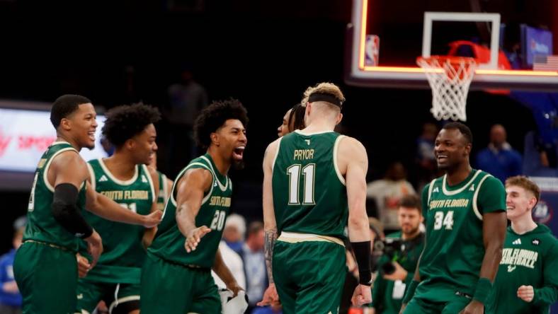 South Florida's Sam Hines Jr. (20) slaps Kasean Pryor (11) on the back as the team celebrates as the buzzer sounds after defeating Memphis 74-73 at FedExForum in Memphis, Tenn., on Thursday, January 18, 2024.