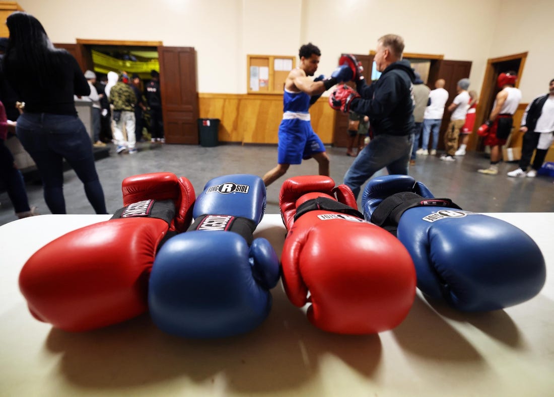 Michael Cappiello owner of Cappiello Boxing Gym with his boxer Will Longwe, 27, who hits the hand pads against Mchilandy Noel of Bishop's Gym in West Bridgewater during the Southern New England Golden Gloves opening night at the Fall River PAL Hall on Saturday, Jan. 20, 2024.