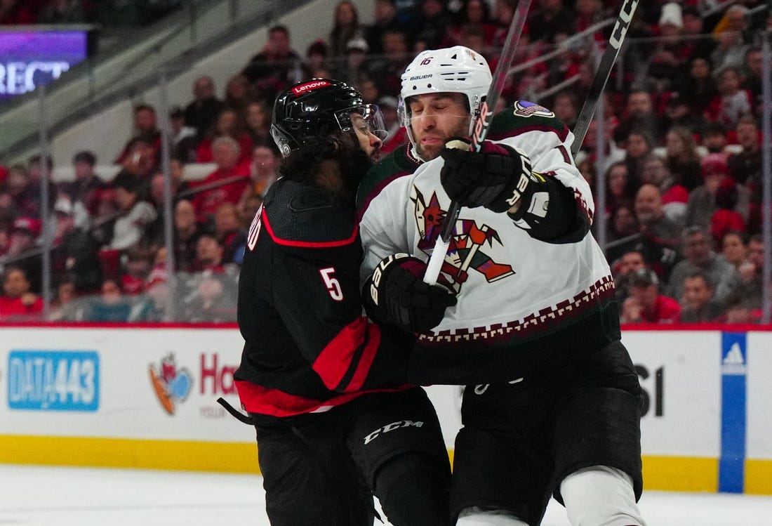 Jan 27, 2024; Raleigh, North Carolina, USA; Arizona Coyotes left wing Jason Zucker (16) checks Carolina Hurricanes defenseman Jalen Chatfield (5) during the first period at PNC Arena. Mandatory Credit: James Guillory-USA TODAY Sports