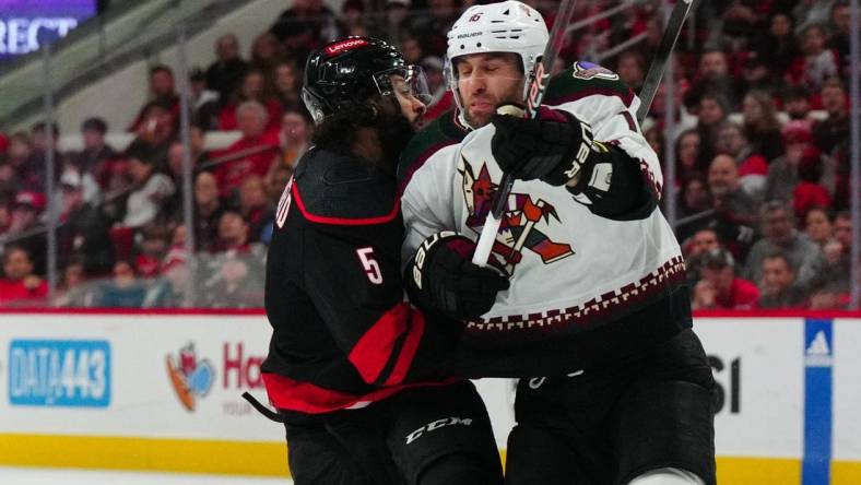 Jan 27, 2024; Raleigh, North Carolina, USA; Arizona Coyotes left wing Jason Zucker (16) checks Carolina Hurricanes defenseman Jalen Chatfield (5) during the first period at PNC Arena. Mandatory Credit: James Guillory-USA TODAY Sports